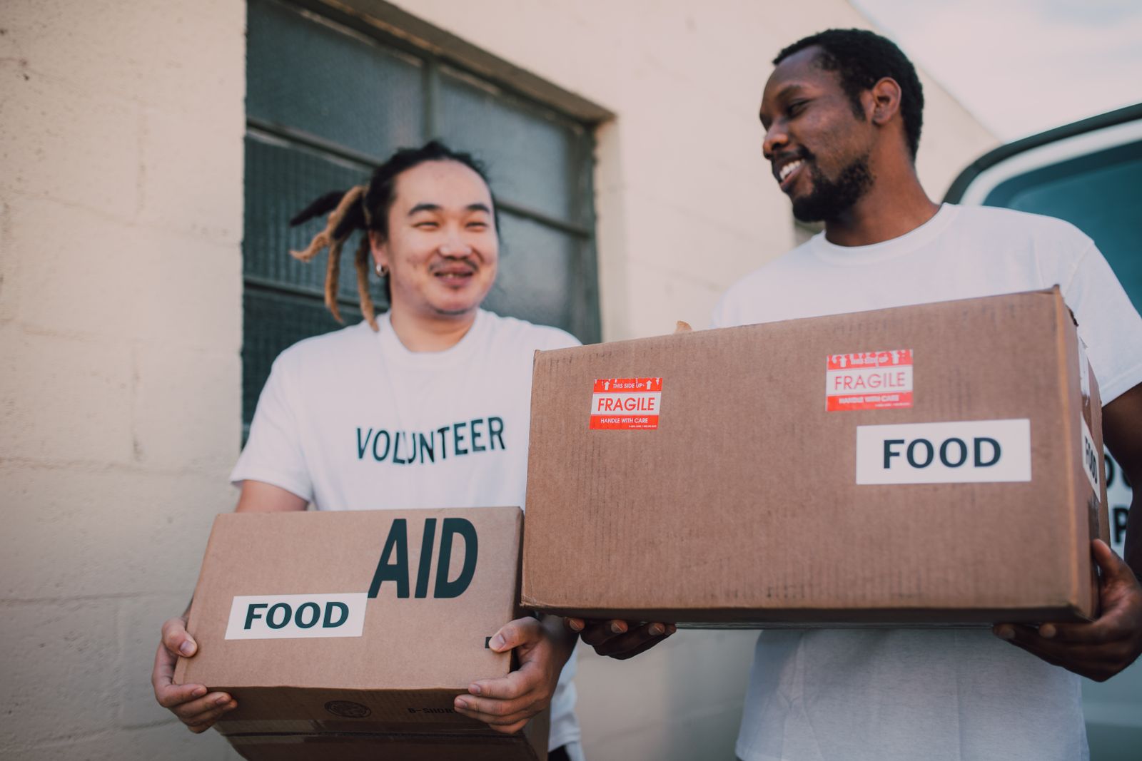 Two volunteers carrying cardboard boxes marked aid and food