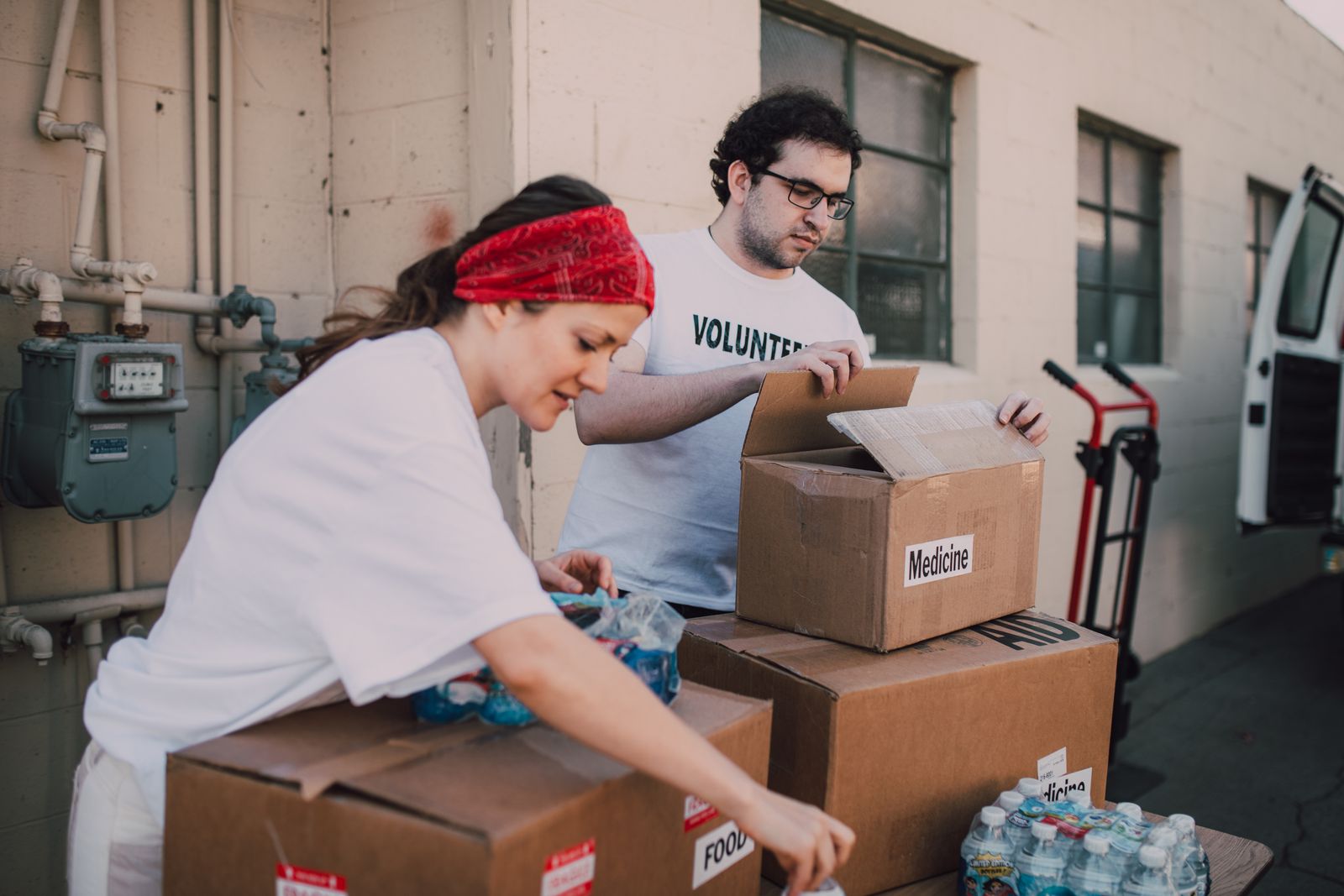 Two volunteers packing supplies into cardboard boxes