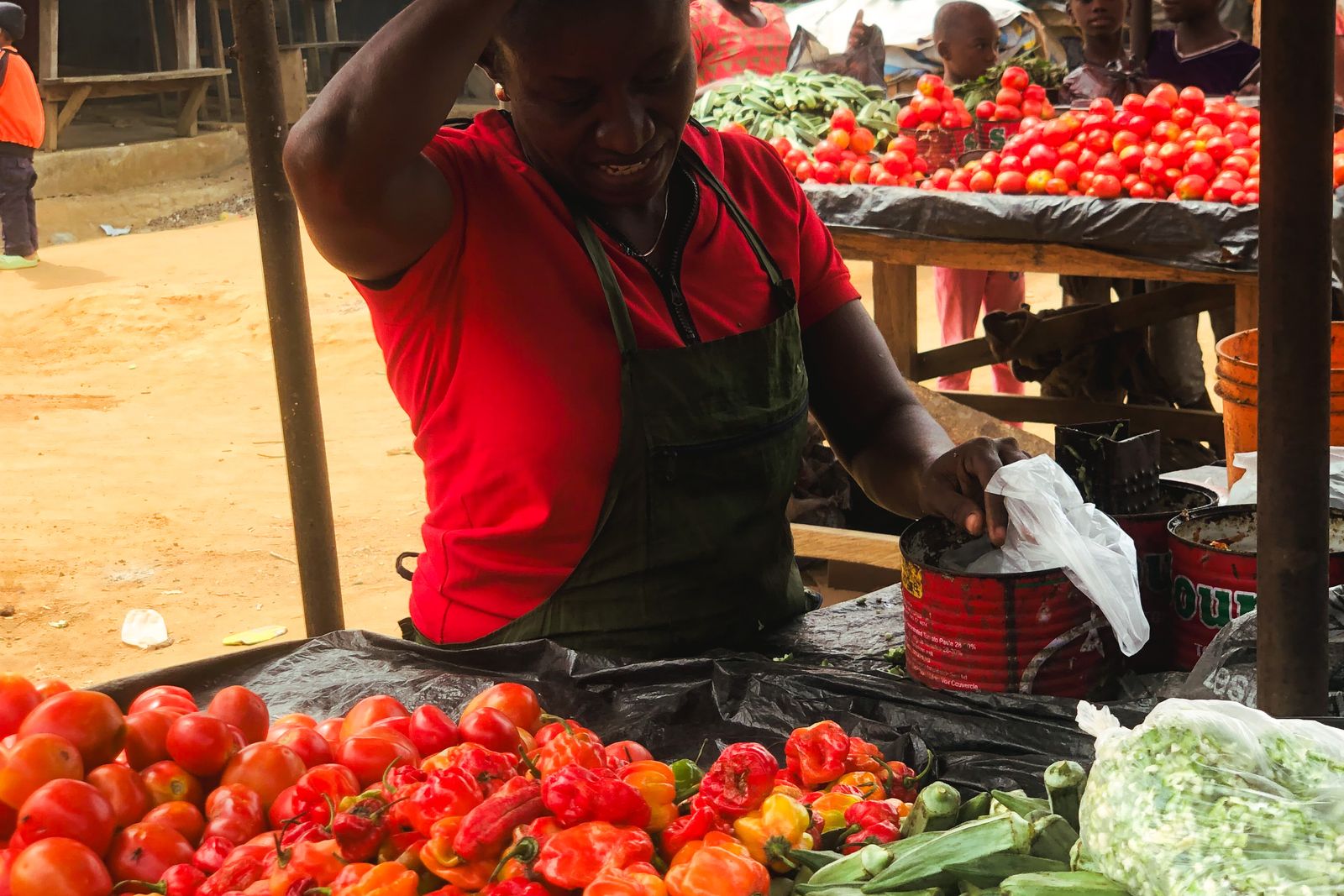 A woman arranging tomatoes and vegetables on her market stall